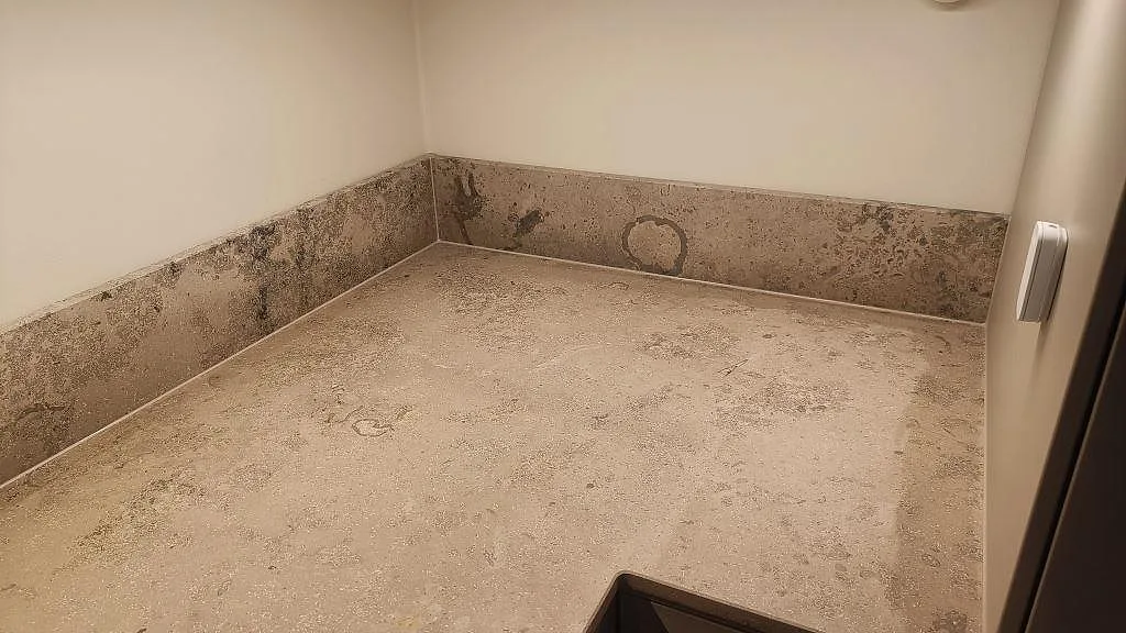Hörnvy av arbetsbänk och stänkkant i matt Jura Grey kalksten i ett kök i Göteborg.