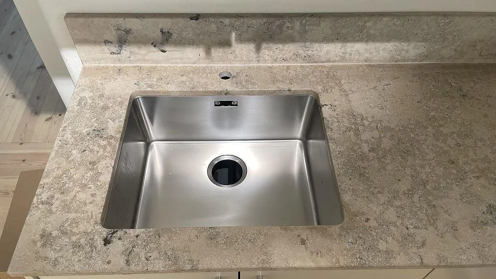 Närbild på matt Jura Grey bänkskiva med ho, stänkkant och tydlig kalkstensstruktur i Göteborg.
