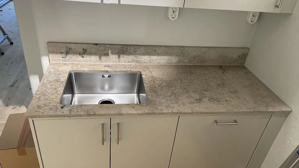 Köksbänkskiva i matt Jura Grey, 20 mm, med låg stänkkant och synlig ho i ett kök i Göteborg.