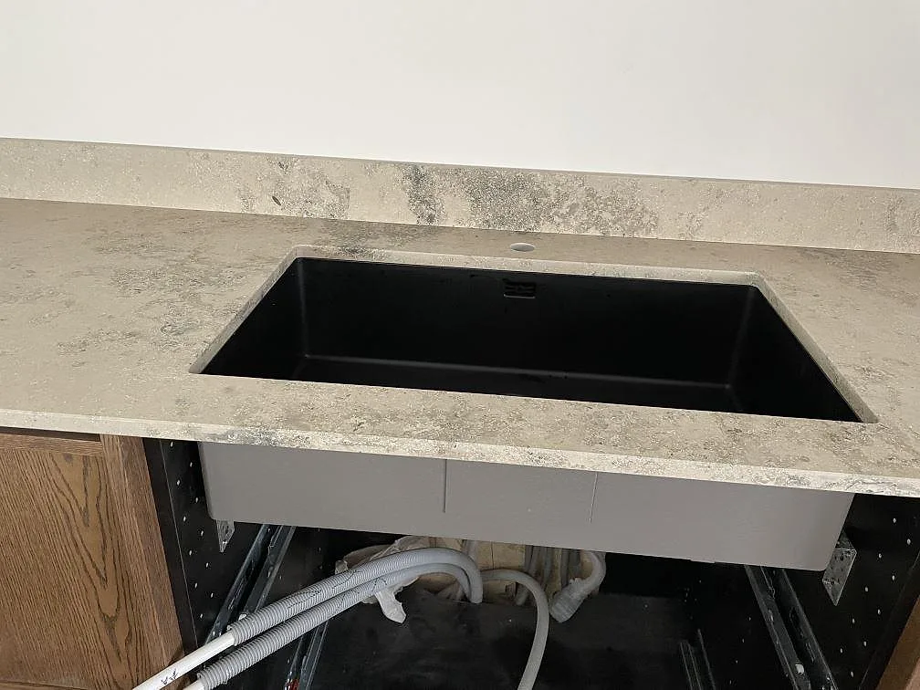 Underlimmad svart kompositdiskho i matt Jura Grey köksbänkskiva i ett kök i Halmstad.