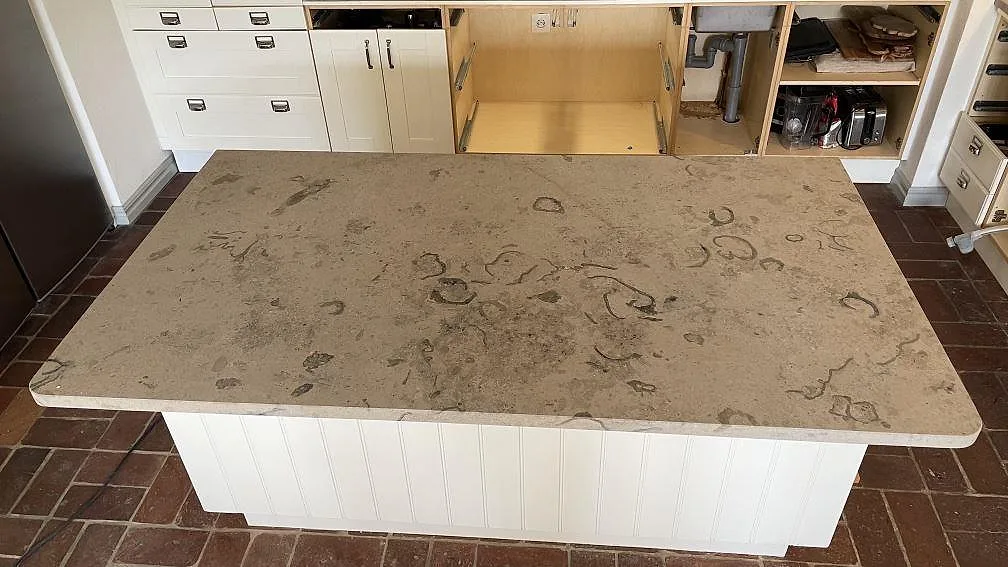 Närbild av köksö i matt Jura Grey kalksten i Helsingborg, med fossil ådring över den installerade bänkskivan.