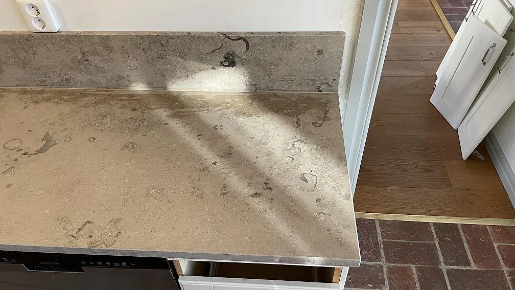 Matt Jura Grey bänkskiva med uppvikt stänkskydd och ljus ådring i ett kök i Helsingborg.