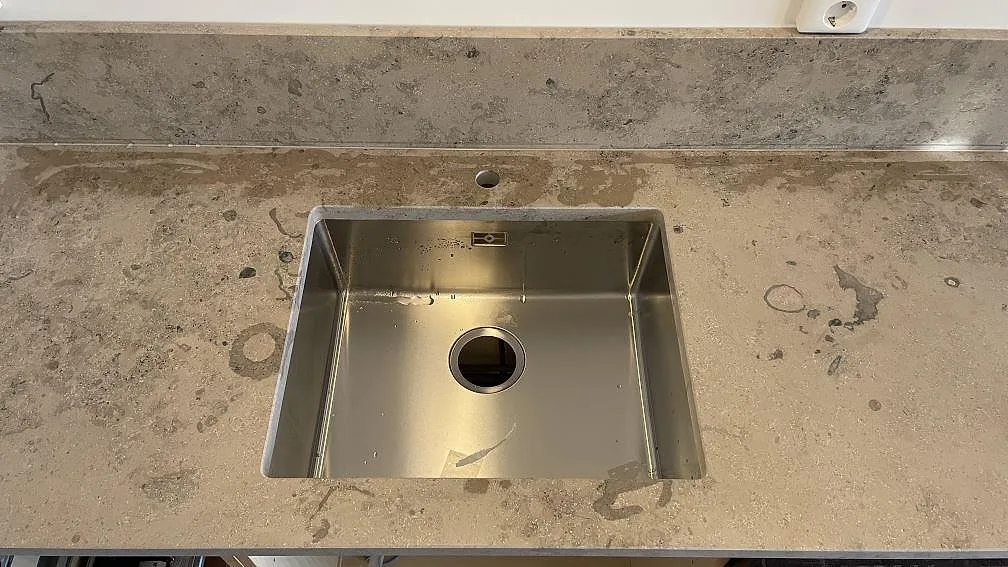 Installerad Jura Grey kalksten i matt finish runt en rostfri diskho och låg stänkkant i Helsingborg.