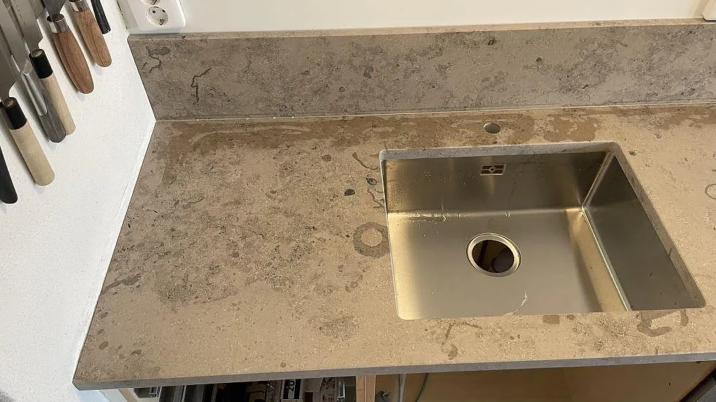 Sidobänk i matt Jura Grey med rostfri diskho, stänkskydd och tydlig kalkstensstruktur i Helsingborg.