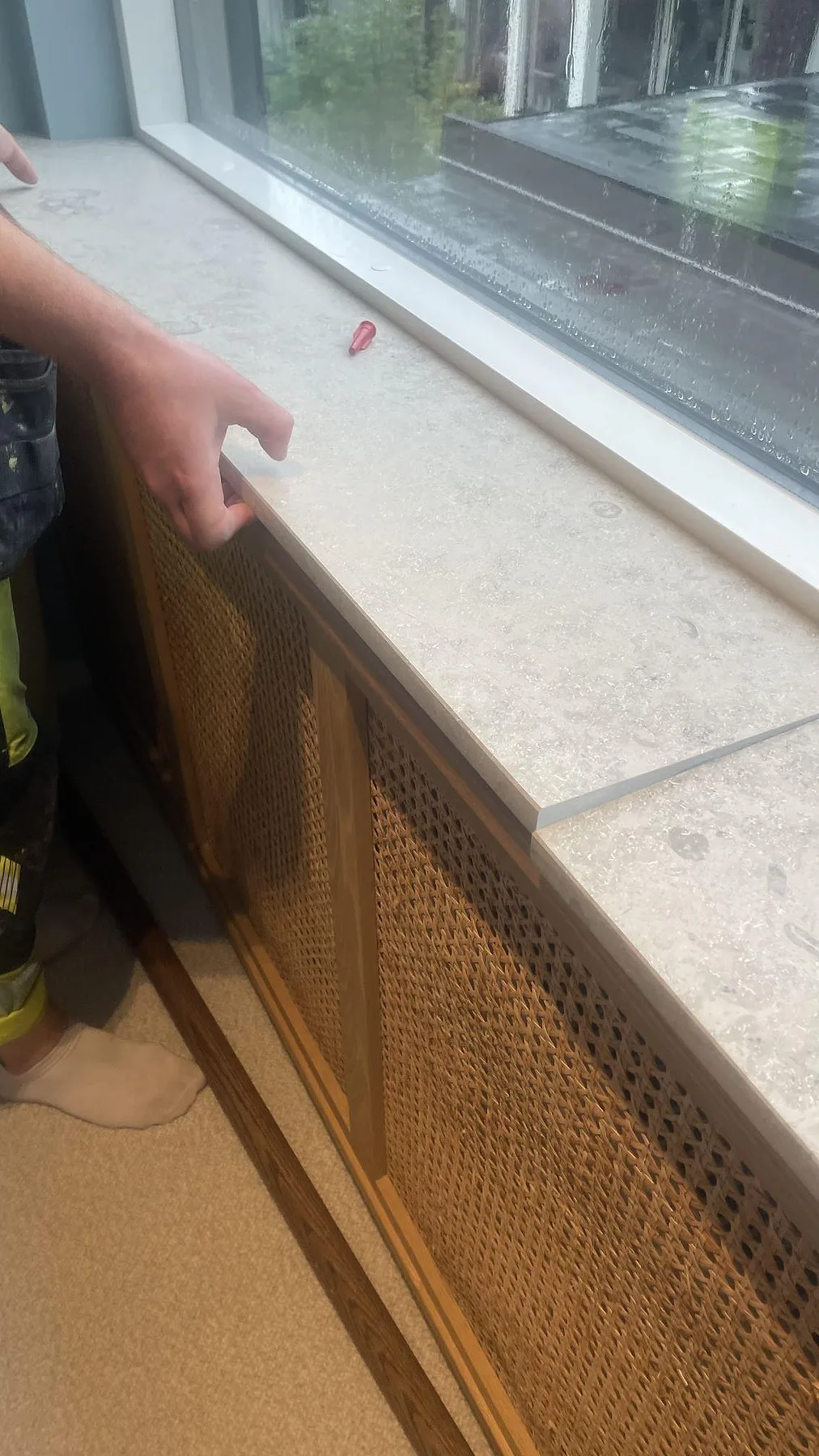 Närbild av matt Jura Grey kalksten som fönsterbänk på en radiatoröverbyggnad med träfronter under montering i Höllviken.