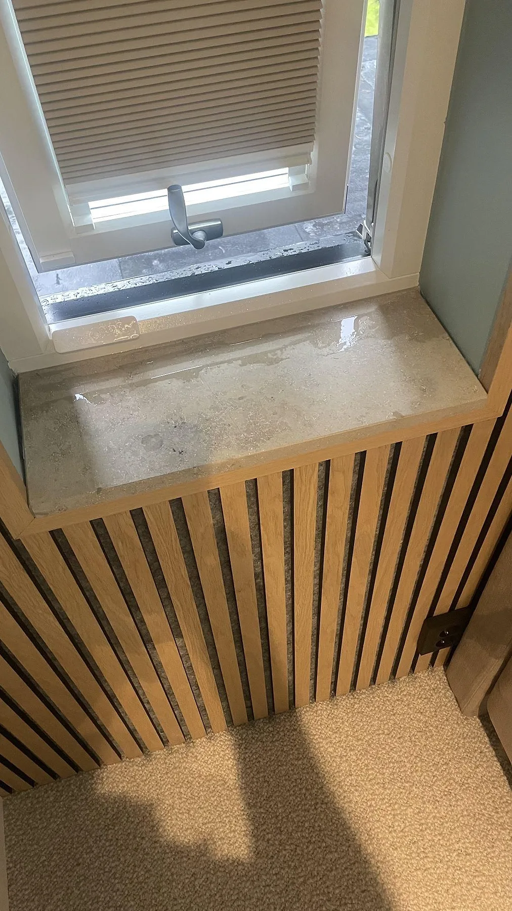 Fönsterbänk i matt Jura Grey kalksten på en träklädd radiatoröverbyggnad med vädringsfönster i Höllviken.
