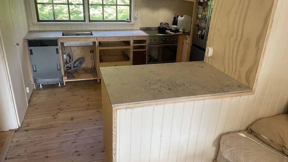 Köksbänkskivor i matt Jura Grey kalksten med separat köksö och bänkrad vid fönster i ett kök under montering i Höör.