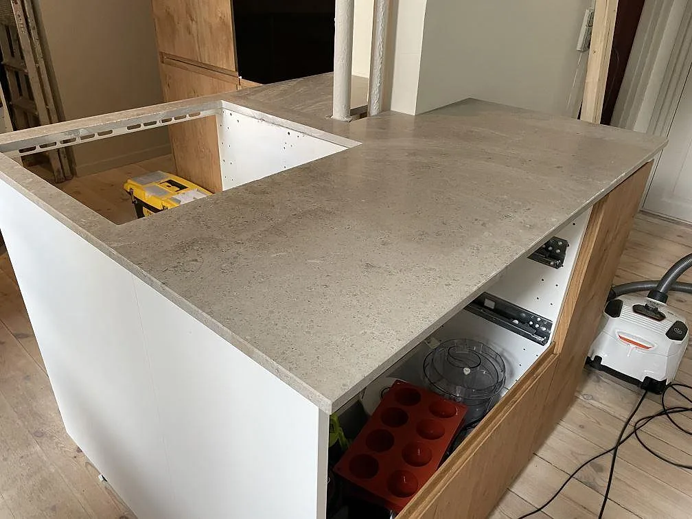 Matt köksbänkskiva i Jura Grey på vit köksstomme, med halvö och diskhoutsnitt under montering i København.