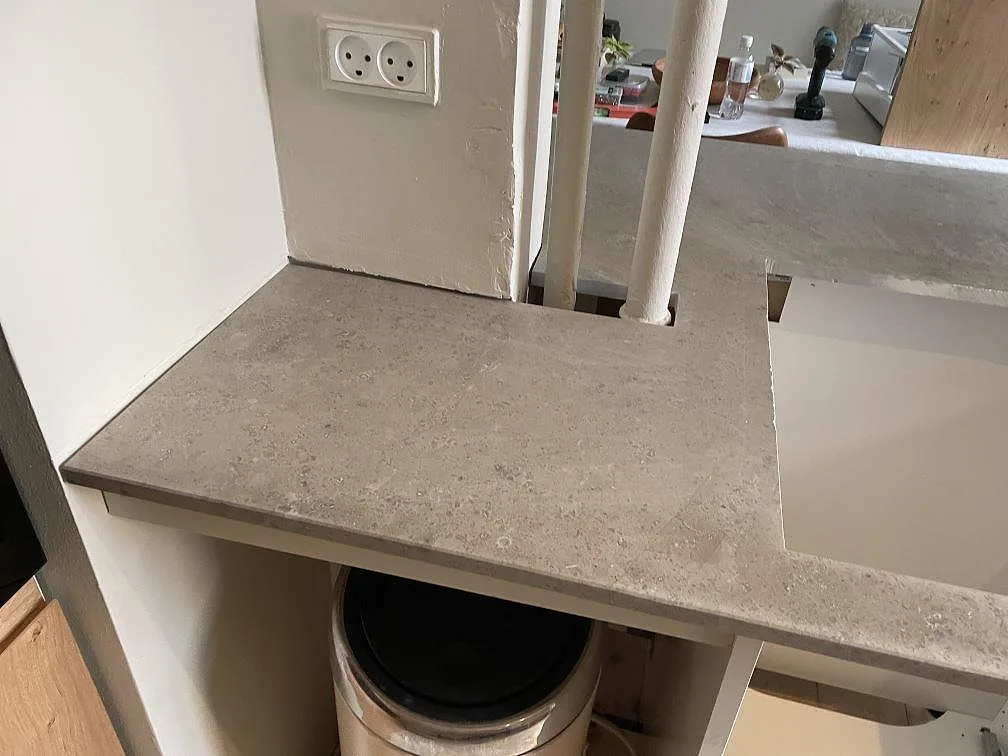 Detalj av matt Jura Grey bänkskiva runt rör och diskhoutsnitt, monterad på vita stommar i København.