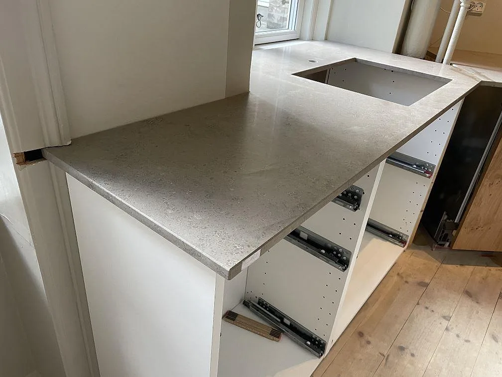 Köksbänkskiva i matt Jura Grey kalksten med underlimmad diskho och halvö i ett kök i København.