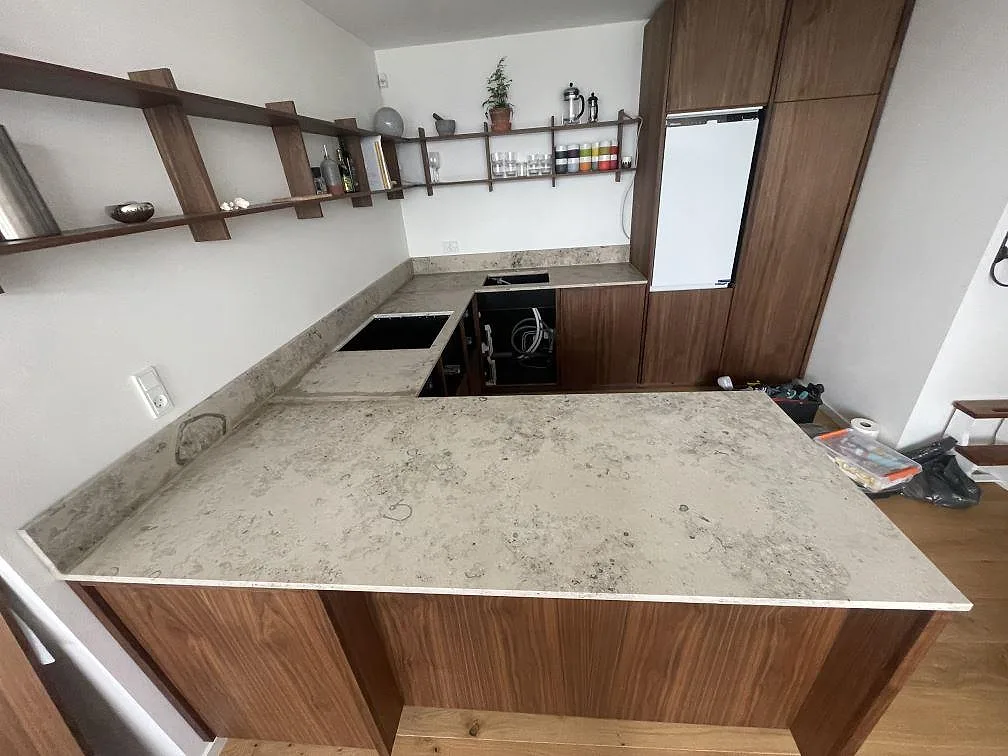 Matt Jura Grey kalksten med fossilådring och förberett urtag för diskho, monterad runt tre sidor i ett valnötskök i København.