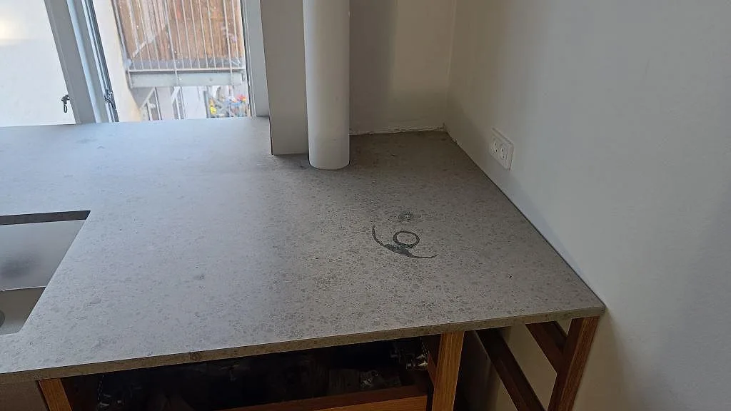Underlimmad rostfri diskho i matt Jura Grey kalkstensbänk i ett kök i København N.