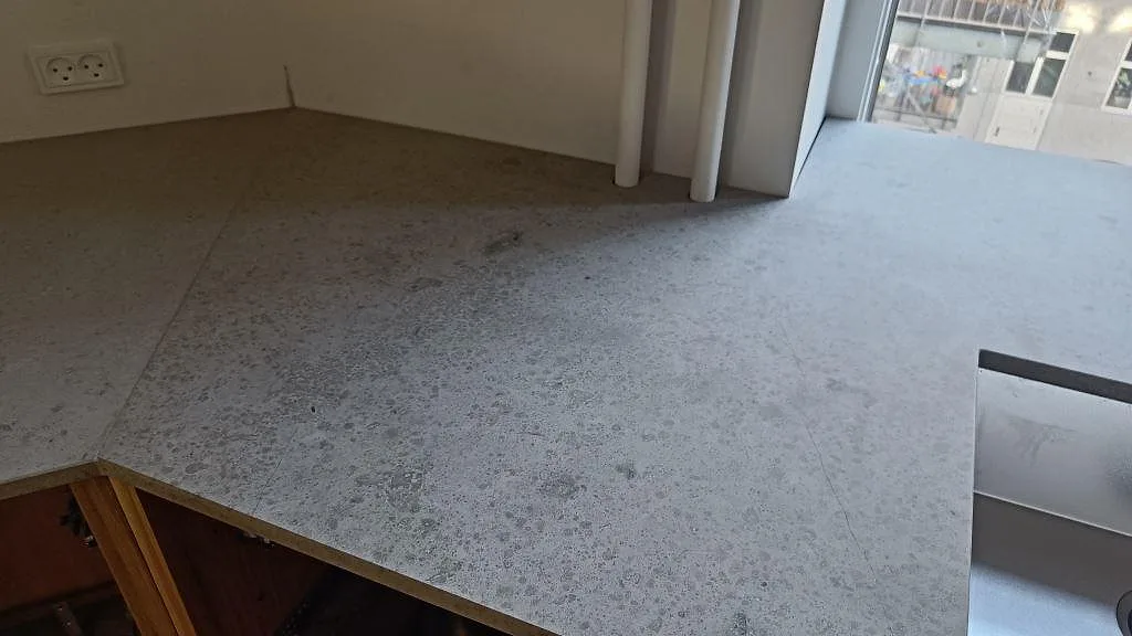 Matt Jura Grey kalkstensbänk monterad i situ längs köksvägg med fönster, fotad under montering i København N.