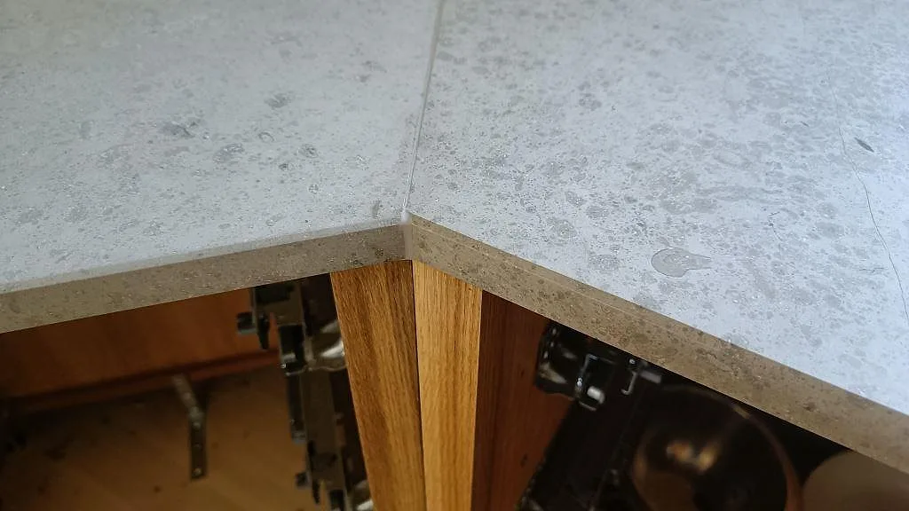 Närbild på mitrad kantprofil och fossila inslag i den matta Jura Grey kalkstensbänken i ett kök i København N.