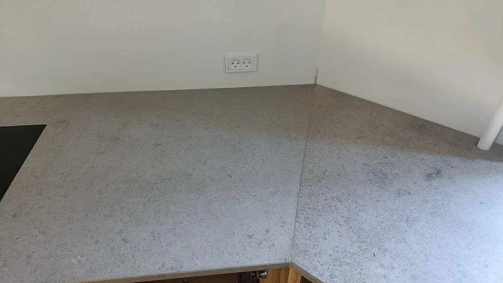 Installerad Jura Grey köksbänkskiva i matt kalksten med urtag för induktionshäll i ett kök i København N.