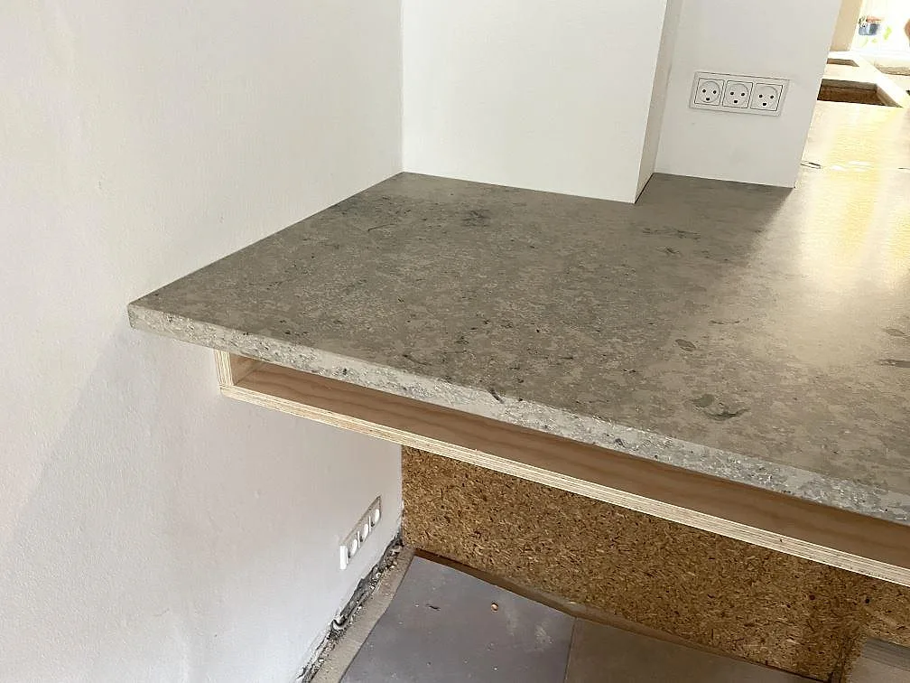 Kantdetalj på matt Jura Grey kalksten vid den rundade halvön i köket i København N.