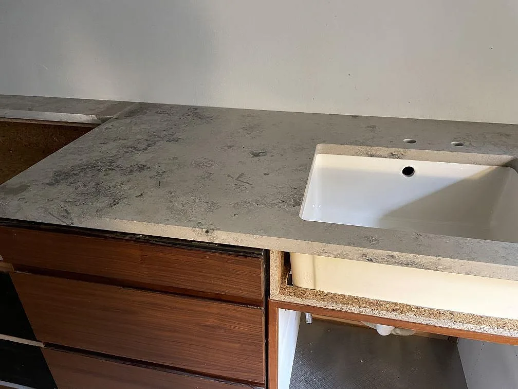Köksbänkskiva i matt Jura Grey kalksten med vit ovanpåliggande diskho och träinredning i København N.