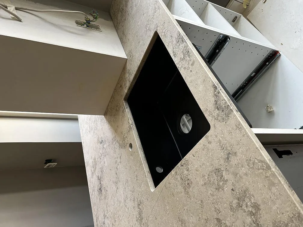Matt Jura Grey köksbänkskiva med underlimmad mörk diskho och kran-hål, fossilådrad kalksten i ett kök i København Ø.