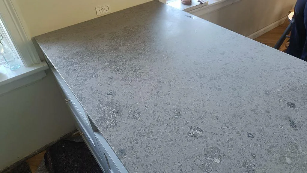 Installerad halvö i matt Jura Grey kalksten vid fönster med vit köksinredning i Köpenhamn.