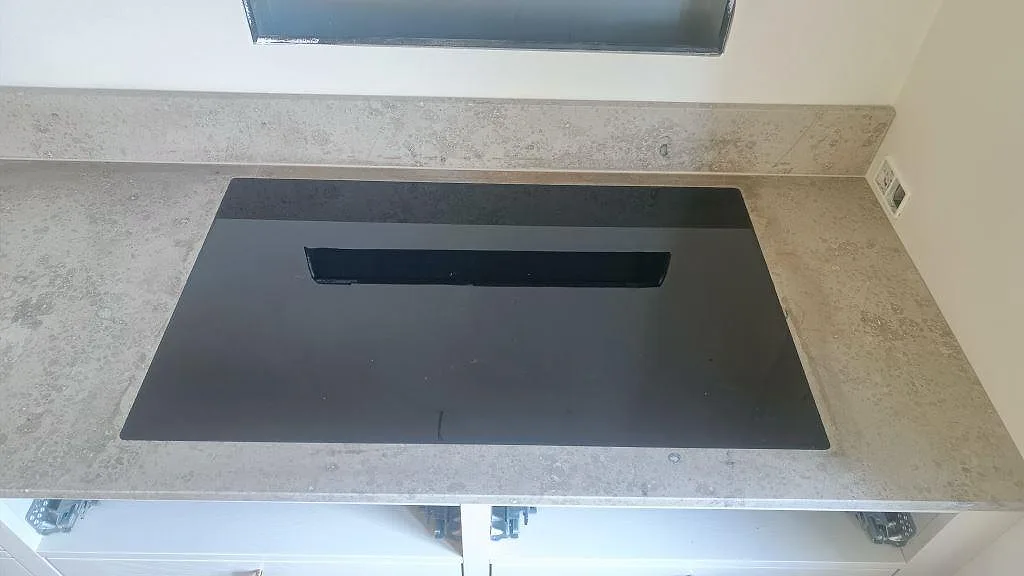 Svart induktionshäll infälld i en matt Jura Grey köksbänkskiva med uppvikt stänkkant i Köpenhamn.