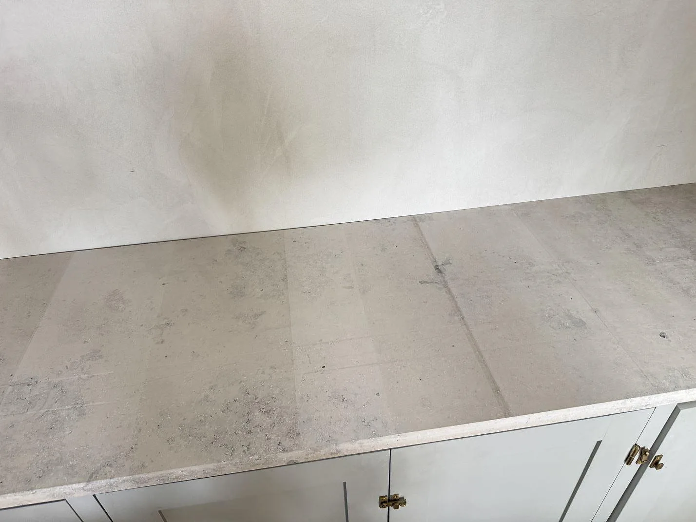 Närbild på matt Jura Grey köksbänkskiva med fossilrikt gråbeige stenuttryck och ljusa skåpluckor i Köpenhamn.
