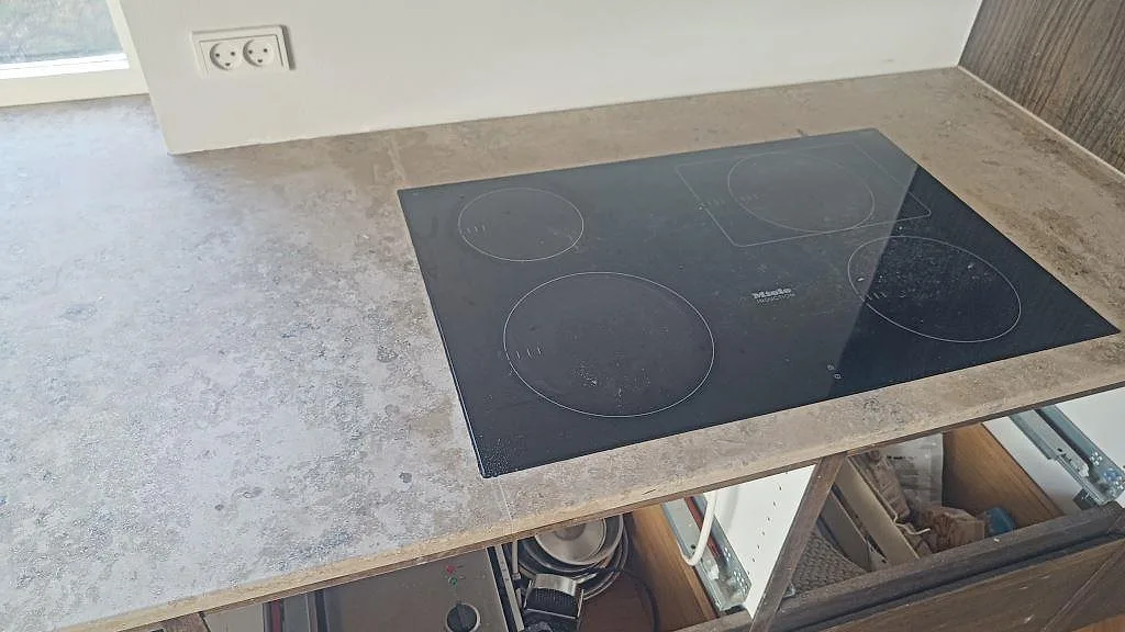 Matt Jura Grey kalkstensbänk med infälld svart induktionshäll och fönster ovanför i ett kök i Kongens Lyngby.