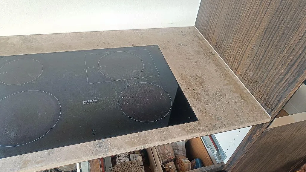 Närbild på infälld Miele induktionshäll i en matt Jura Grey kalkstensbänk i ett kök i Kongens Lyngby.