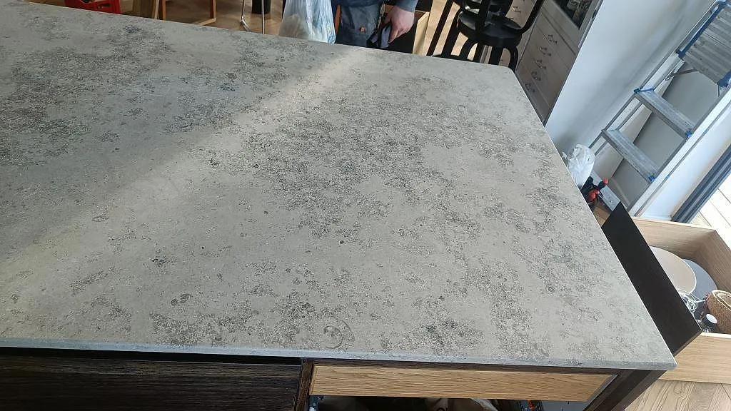 Detalj av induktionshäll plant infälld i matt Jura Grey kalksten mot räfflad träinredning i ett kök i Kongens Lyngby.
