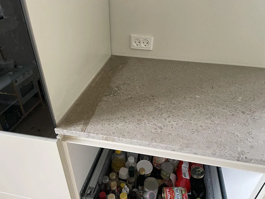 Detaljbild av matt Jura Grey kalksten med grå fossilådring på bänkskiva intill högskåp i Kongens Lyngby.