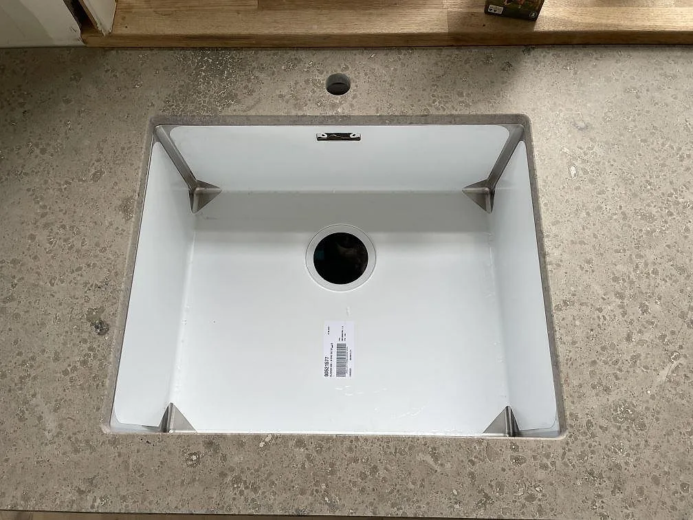 Detalj av vit underlimmad diskho i köksbänkskiva av matt Jura Grey kalksten i Kongens Lyngby.