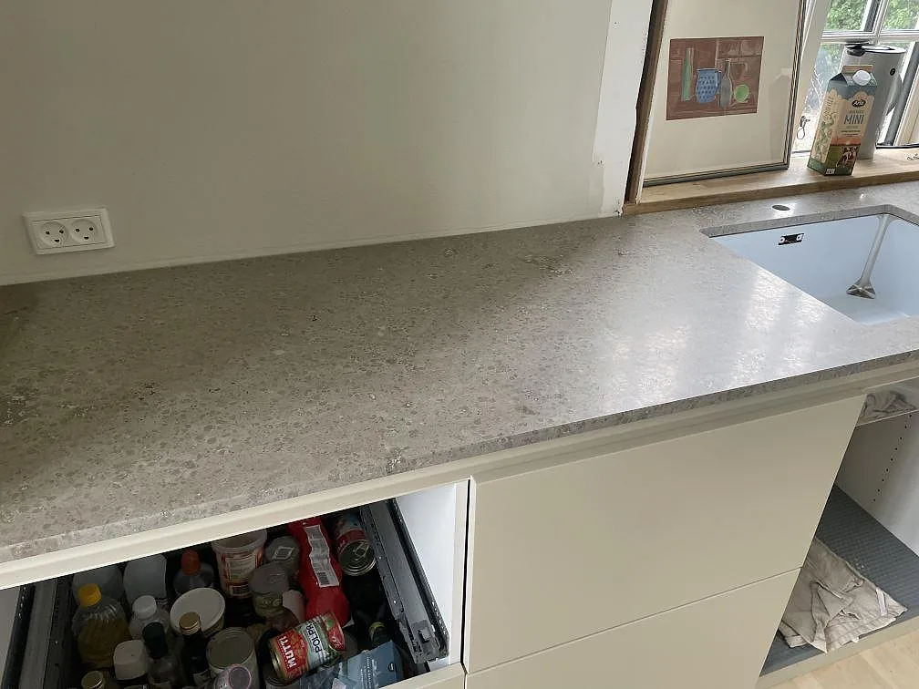 Köksbänkskiva i matt Jura Grey kalksten med vit underlimmad diskho vid fönster i Kongens Lyngby.