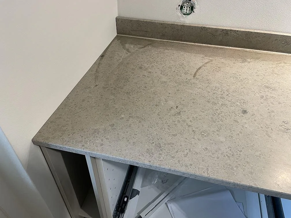 Matt Jura Grey köksbänkskiva med fossil ådring och uppvikt stänkkant över köksstommar i Kortedala.