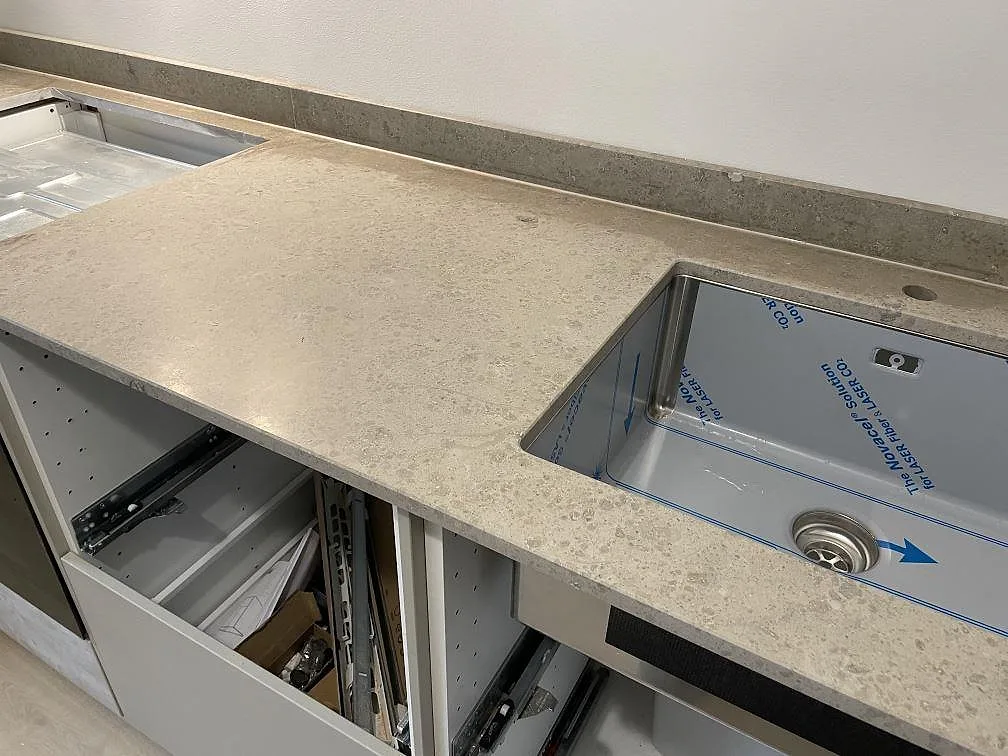 Köksbänkskiva i matt Jura Grey kalksten med rostfri underlimmad diskho och hällurtag under montering i Kortedala.