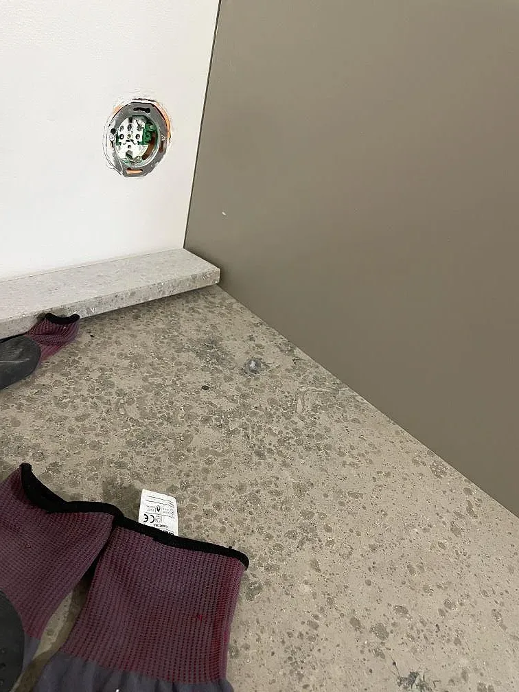Närbild på matt Jura Grey kalksten med fossil struktur och stänkkant vid vägguttag i köket i Kortedala.