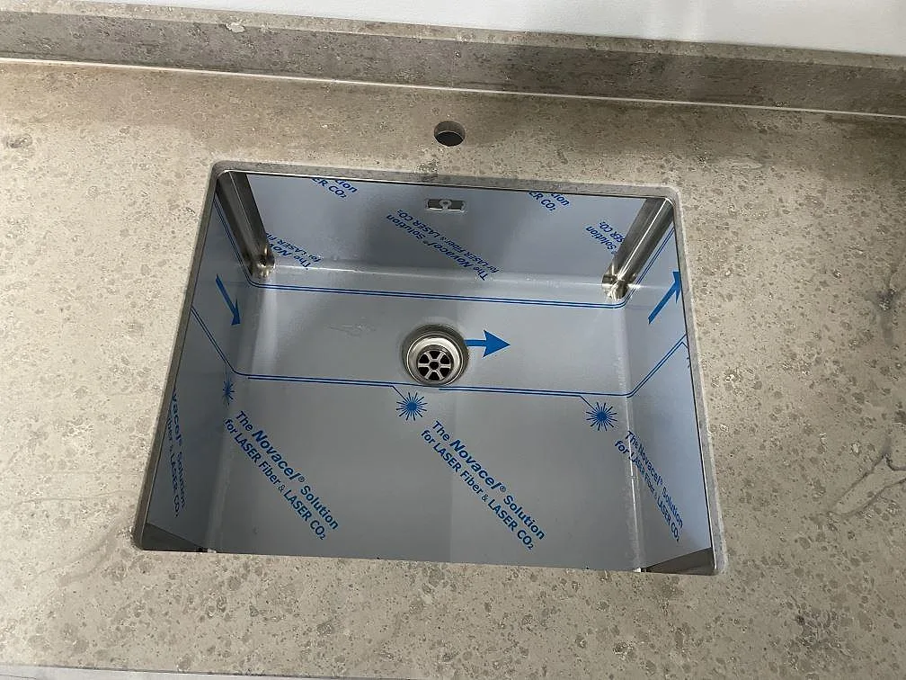 Närbild på underlimmad rostfri diskho i en 20 mm matt Jura Grey bänkskiva med stänkkant i Kortedala.