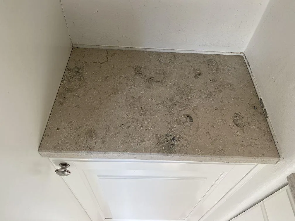 Närbild ovanifrån på matt Jura Grey kalksten med fossilavtryck på en köksbänk i Landskrona.