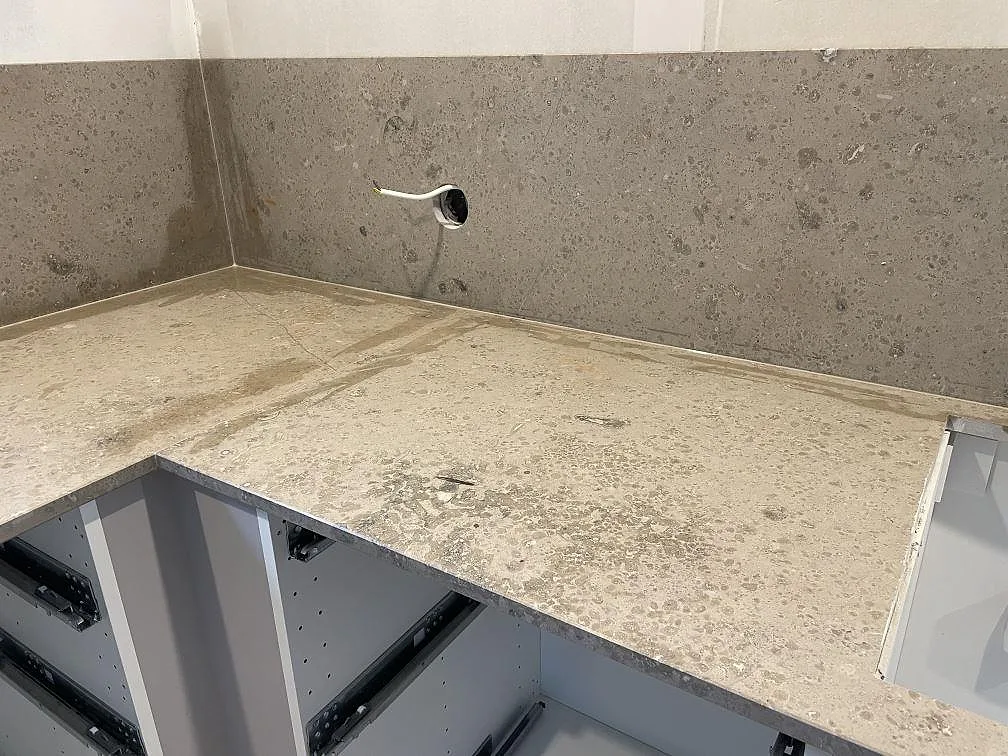 Arbetsyta i matt Jura Grey kalksten med stänkskydd och eluttag under montering i ett kök i Lekeryd.