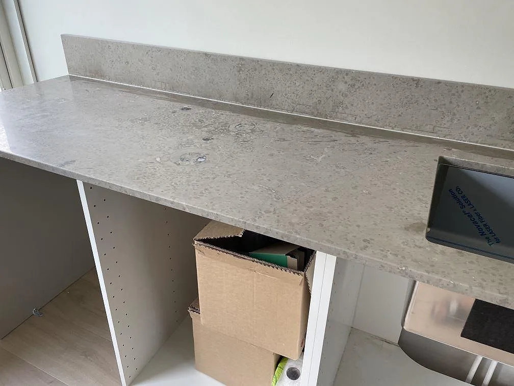 Lång köksbänkskiva i matt Jura Grey kalksten med underlimmad diskho och uppvikt stänkkant i Lindome.