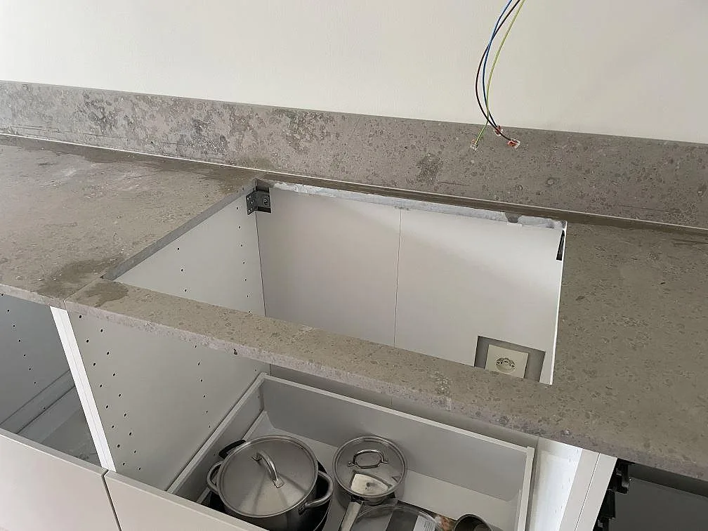Hällöppning i matt Jura Grey köksbänkskiva med uppvikt stänkkant under montering i Lindome.