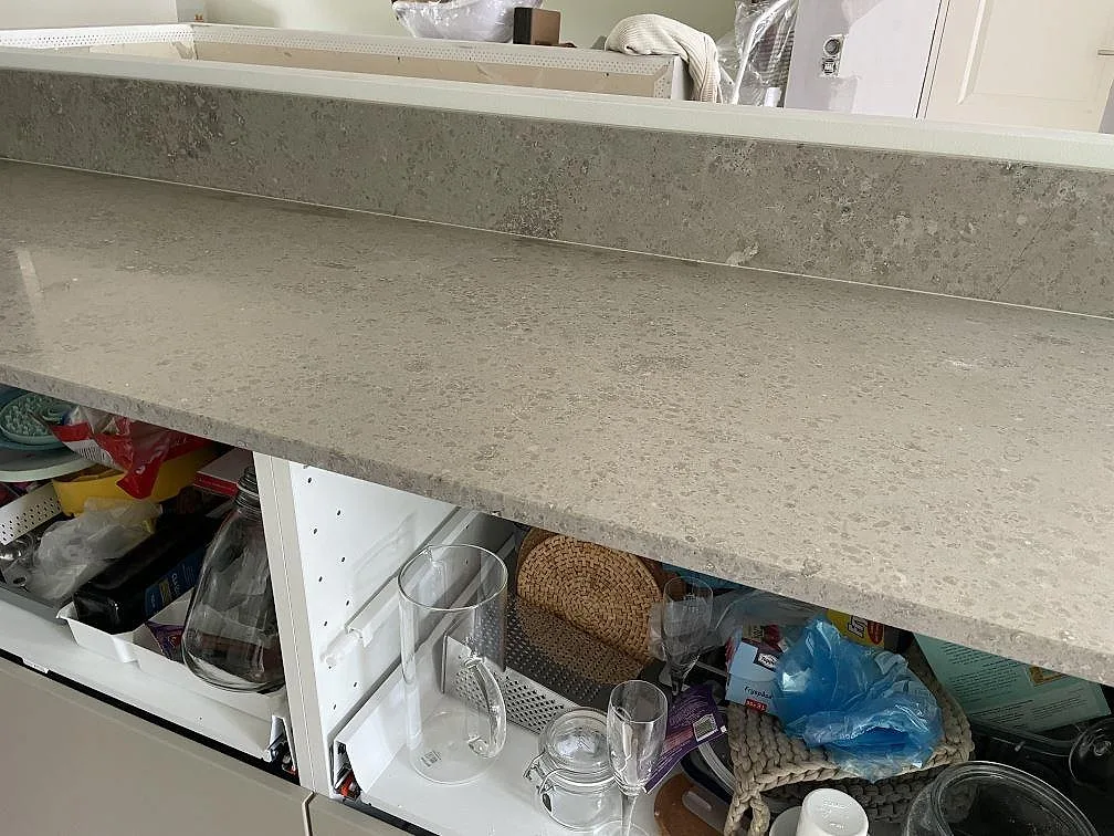 Ytbild av matt Jura Grey kalksten som lång köksbänkskiva med öppna vita stommar i Lindome.