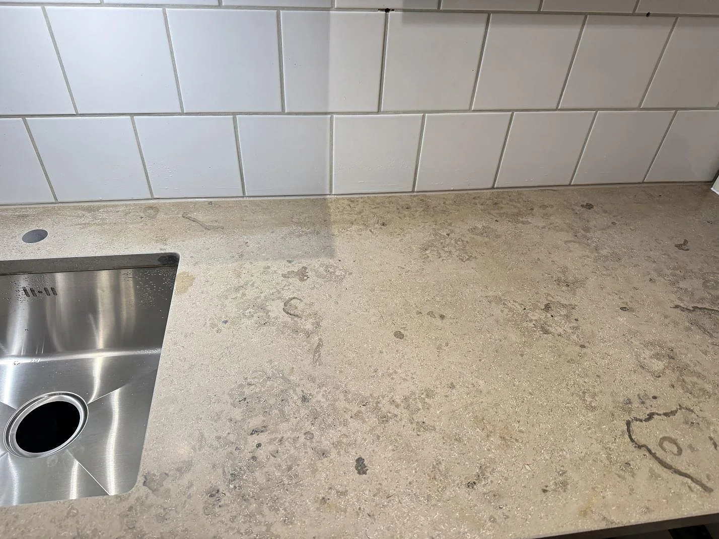 Närbild av matt Jura Grey kalksten som köksbänkskiva i Lund, med diskho i ena änden och fossilteckning över ytan.