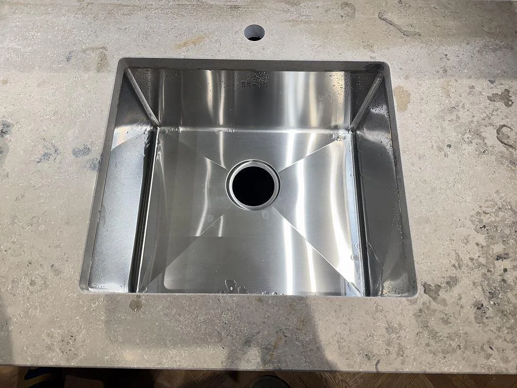 Detalj av diskho i en matt köksbänkskiva av Jura Grey kalksten, med gråbeige ådring i ett kök i Lund.