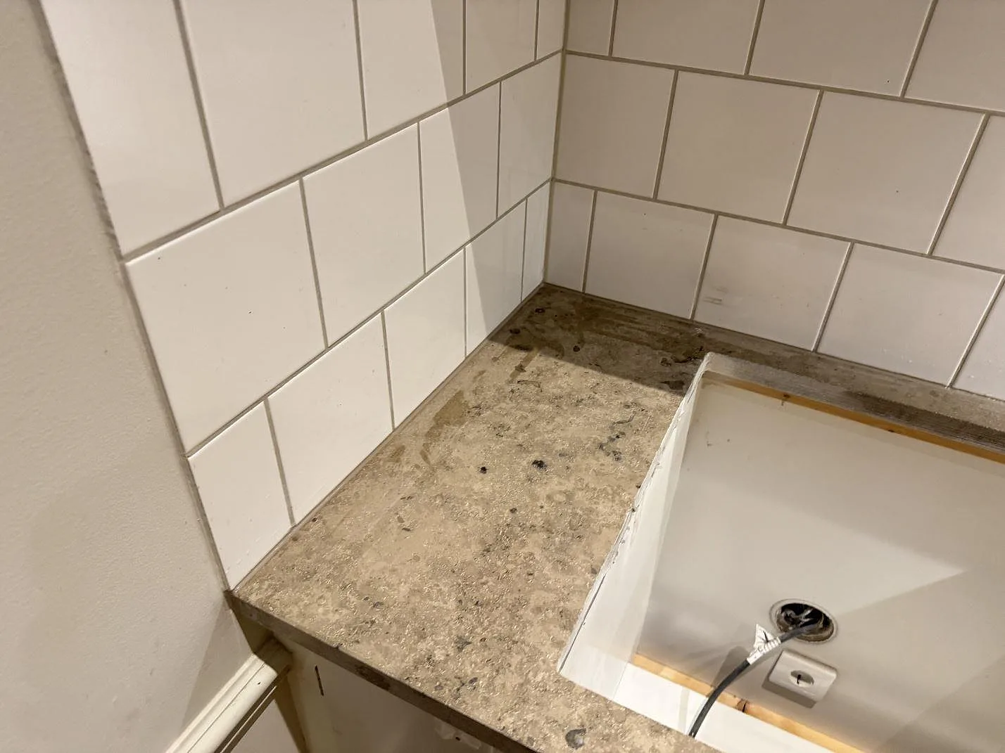 Kort bänkskivedel i matt Jura Grey kalksten vid fönster i ett kök i Lund, med vitt kakel och synligt avslut mot väggen.