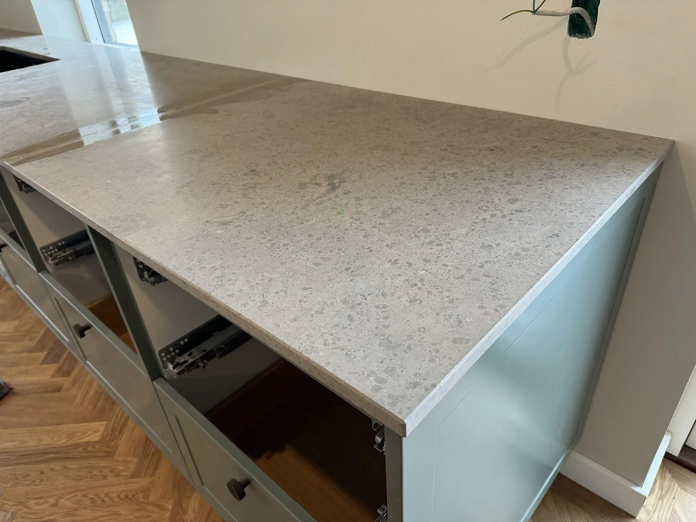 Närbild på matt Jura Grey bänkskiva med gråbeige ådring över grågröna stommar i Lyngby.