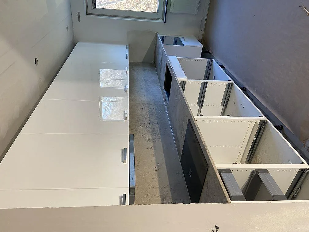 Montering av Jura Grey köksbänkskiva i matt kalksten över vita köksskåp med stänkskydd i samma sten, i ett kök i Malmö.