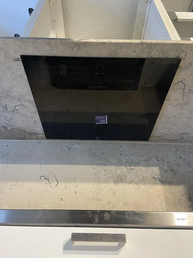 Jura Grey köksbänkskiva i matt kalksten med övermonterad induktionshäll och stänkskydd i sten i ett kök i Malmö.