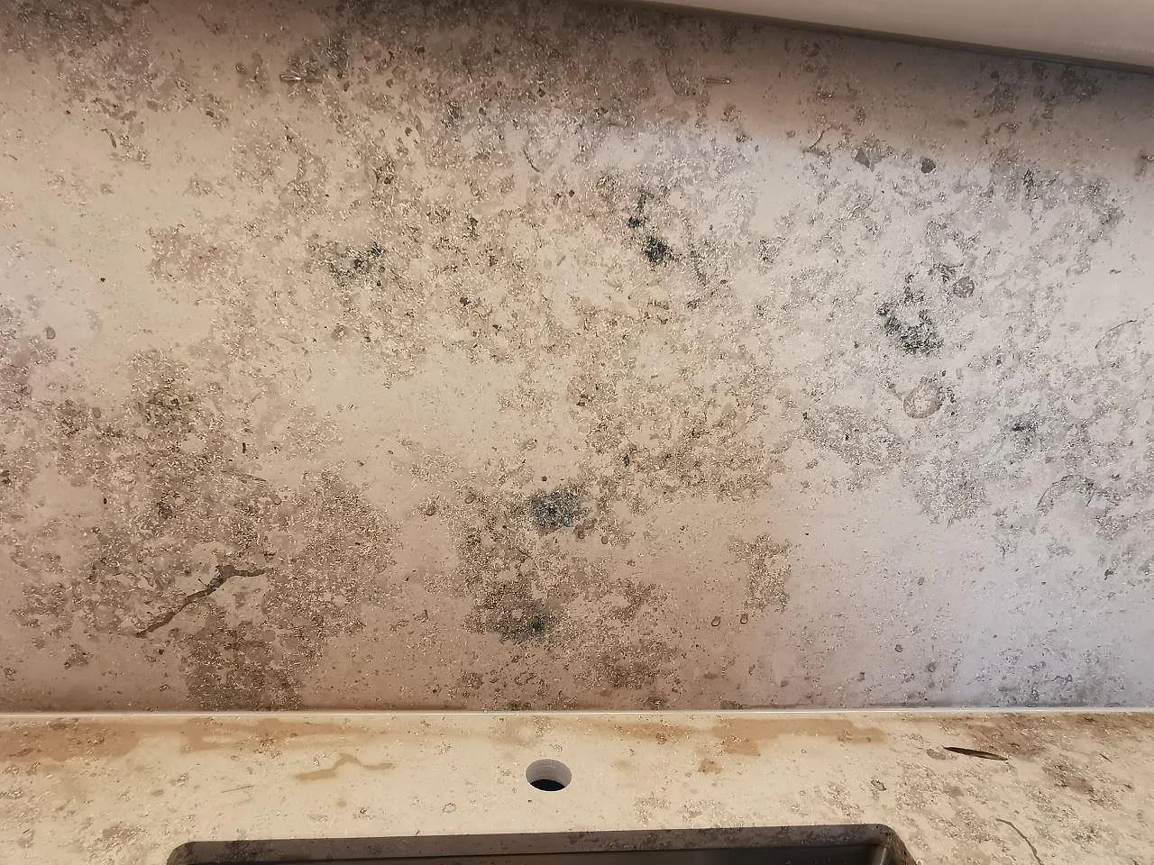 Stänkskydd i Jura Grey kalksten ovanför matt köksbänkskiva med blandarehål, fossilrik kalksten i Malmö.