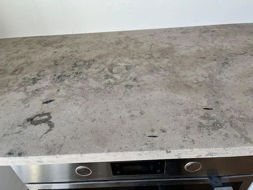 Matt Jura Grey köksbänkskiva med borrade blandarhål ovanför inbyggd ugn i ett kök i Malmö.
