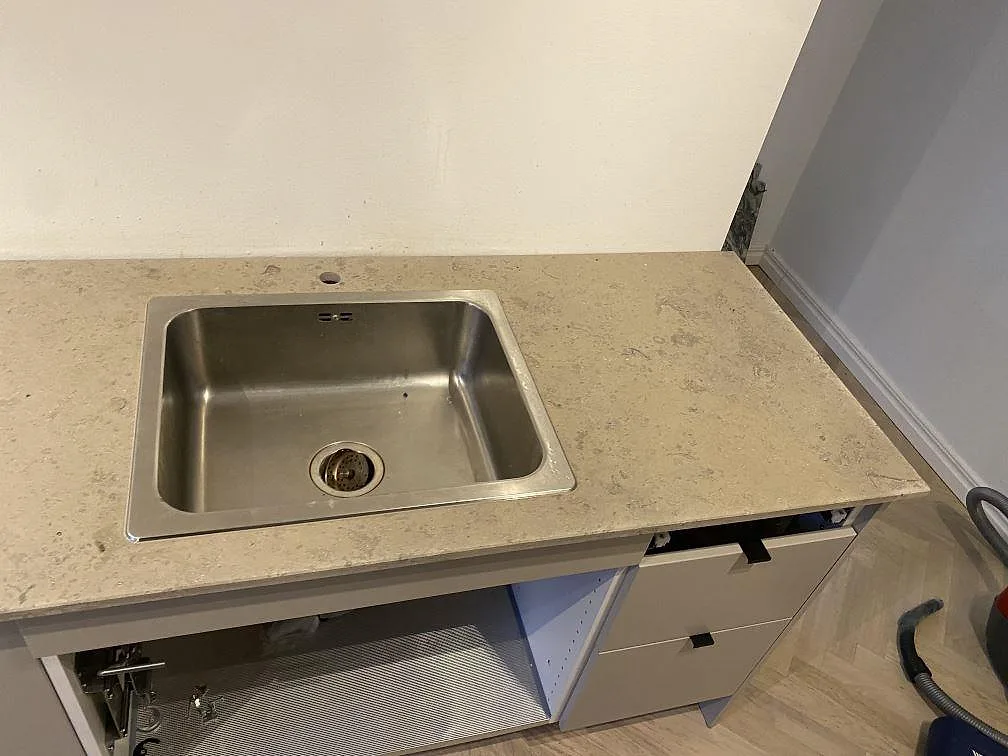 Detalj av underlimmad rostfri diskho i en matt Jura Grey köksbänkskiva i kalksten i ett kök i Malmö.