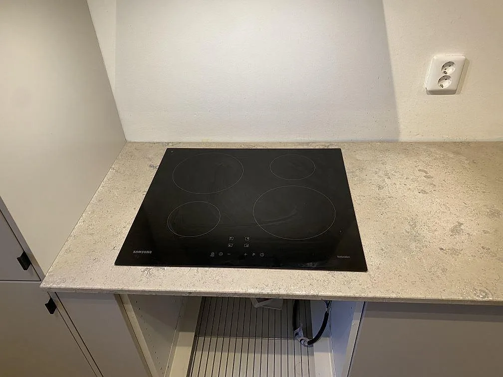 Detalj av induktionshäll infälld i en matt Jura Grey köksbänkskiva i kalksten i ett kök i Malmö.
